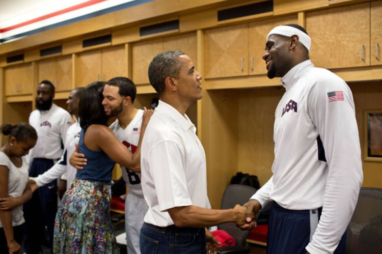Foto von Präsident Barack Obama im Gespräch mit LeBron James, während First Lady Michelle Obama Deron Williams umarmt, beim Treffen mit Mitgliedern des US-Olympia-Basketballteams der Herren.