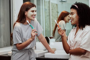 Freundinnen beim gemeinsamen Zähneputzen im Bad mit Gesichtsmaske