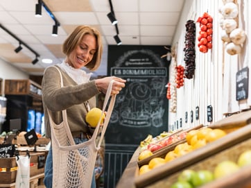 Frau sammelt beim Einkaufen im Supermarkt Obst in einem Netzbeutel