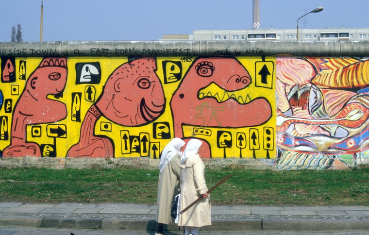 zwei Frauen laufen vor der Berliner Mauer